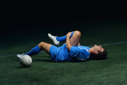 man lying on ground after soccer injury