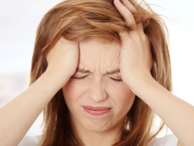 Woman holding hands to forehead because of headaches
