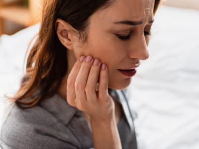 Woman with pain in jaw joint muscle